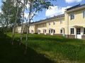Участок перед домом выложен брусчаткой для парковки автомобиля. За домом — газон.